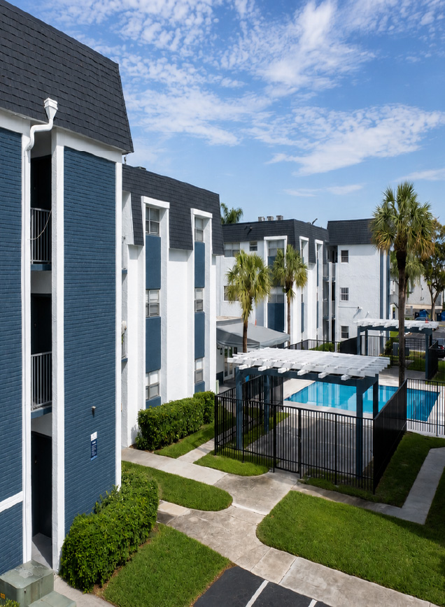Aerial view of Parc Place buildings, palm trees and the fenced pool